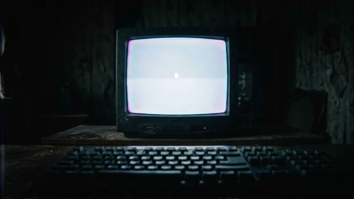 Monitor CRT encendido con la pantalla en blanco y un cursor parpadeando en un cuarto oscuro